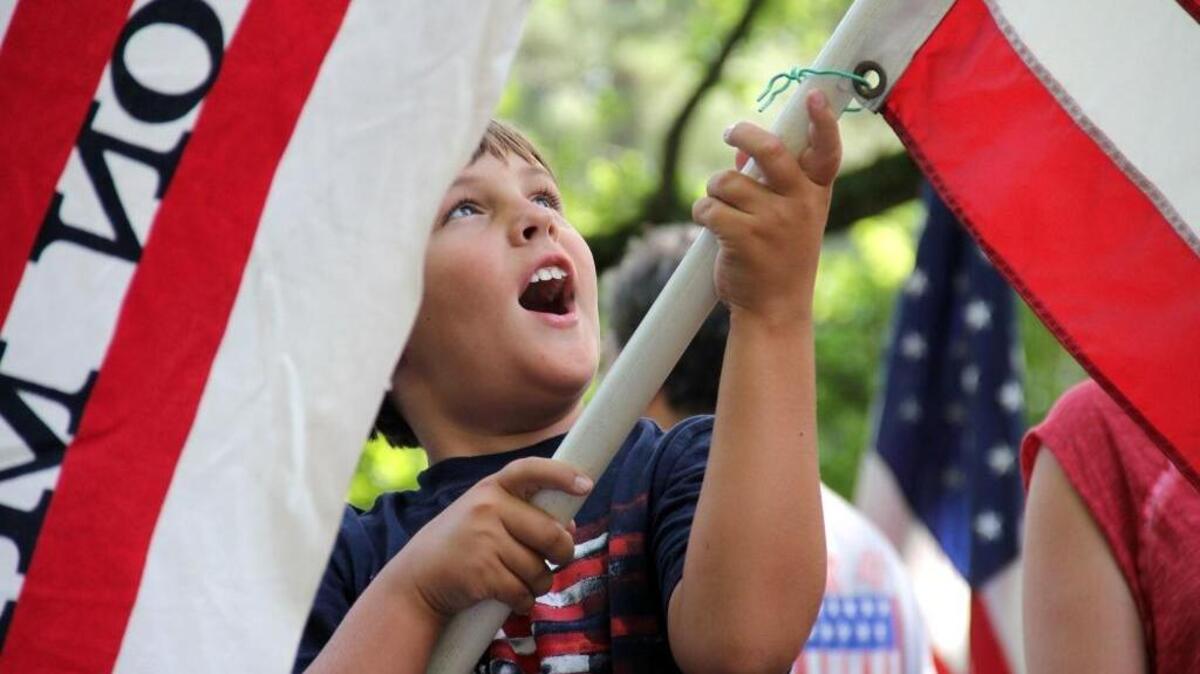 Lachlan Apple, 9, holds a flag used in the first Watts Hospital-Hillandale neighborhood Independence Day parade 66 years ago. This year’s event begins on Tuesday, July 4, at 10 a.m. on the corner of Oakland Avenue and Club Boulevard in Durham.