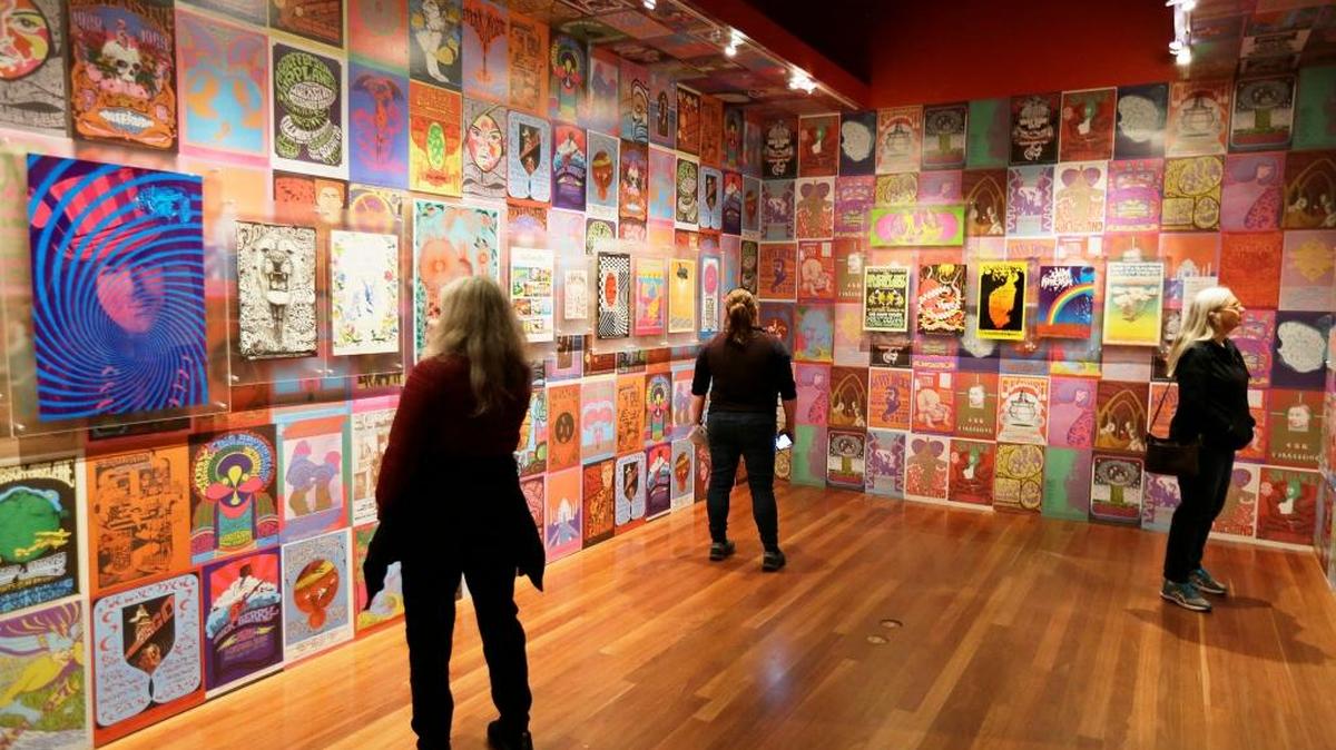 In this Wednesday, May 10, 2017 photo, people look at 1960s music posters display in the exhibit "The Summer of Love Experience, Art, Fashion and Rock and Roll" in Golden Gate Park at the deYoung Museum in San Francisco.