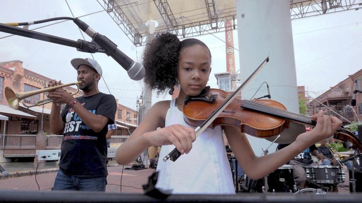 Kidznotes' Sofia Gee plays the violin with jazz artist Al Strong (L) during the Art of Cool concert at Lucky Strike water tower at American Tobacco in April. Art of Cool participated in the Arts & Economic Prosperity study.