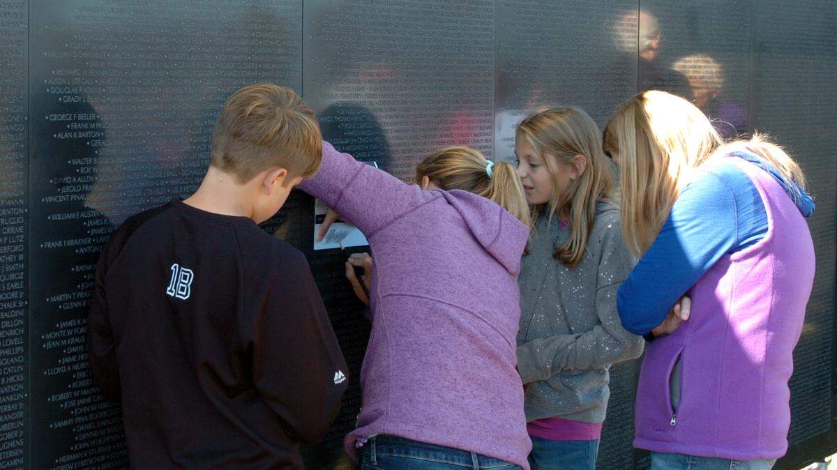 Alison Quinton of Youngsville makes a pencil rubbing Thursday of a name on the Wall that Heals, a three-quarter scale replica of the Vietnam Veterans Memorial, which was making a four-day stop in Wake Forest.