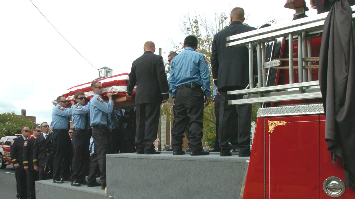 Firefighters from the Orange Rural Fire Department lift the flag-draped casket of Jeffrey Holden onto Engine 4 on Saturday morning.