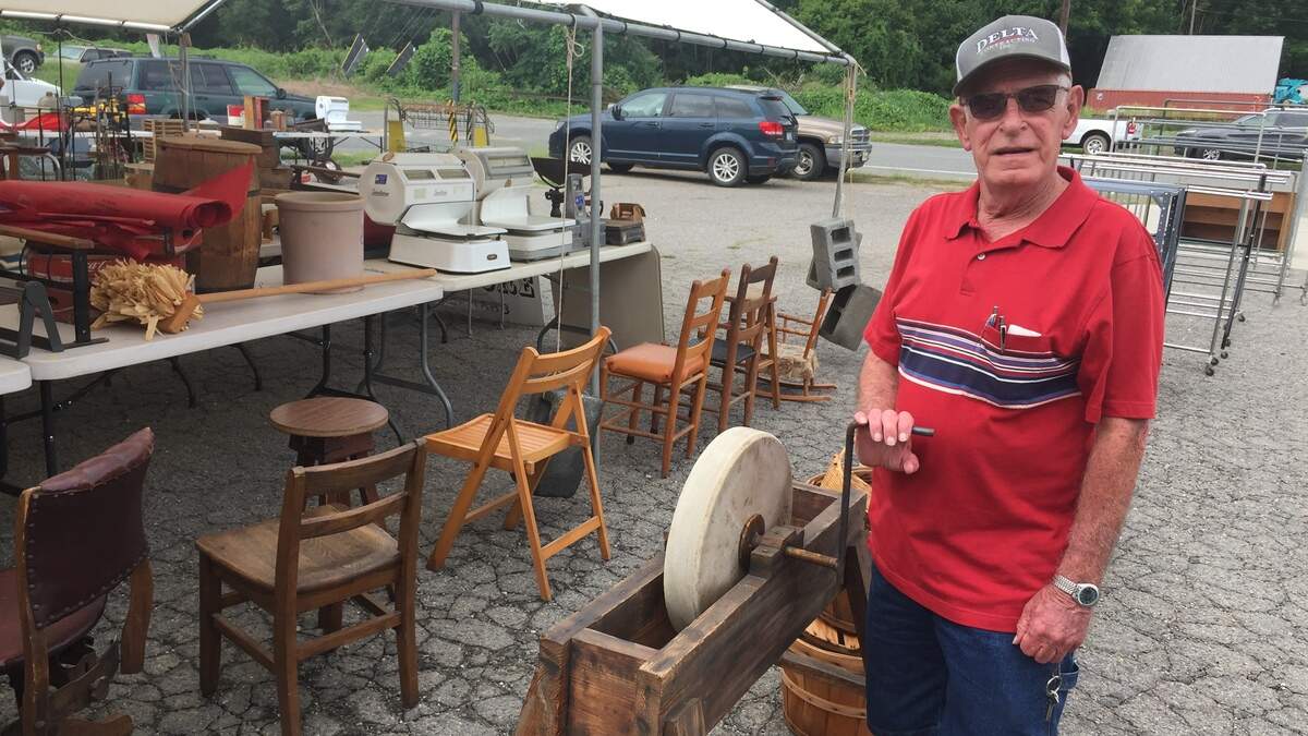 Farmers Alliance Store manager and shareholder Terrill Ellington stands by an old grinding wheel that will be auctioned off Saturday.