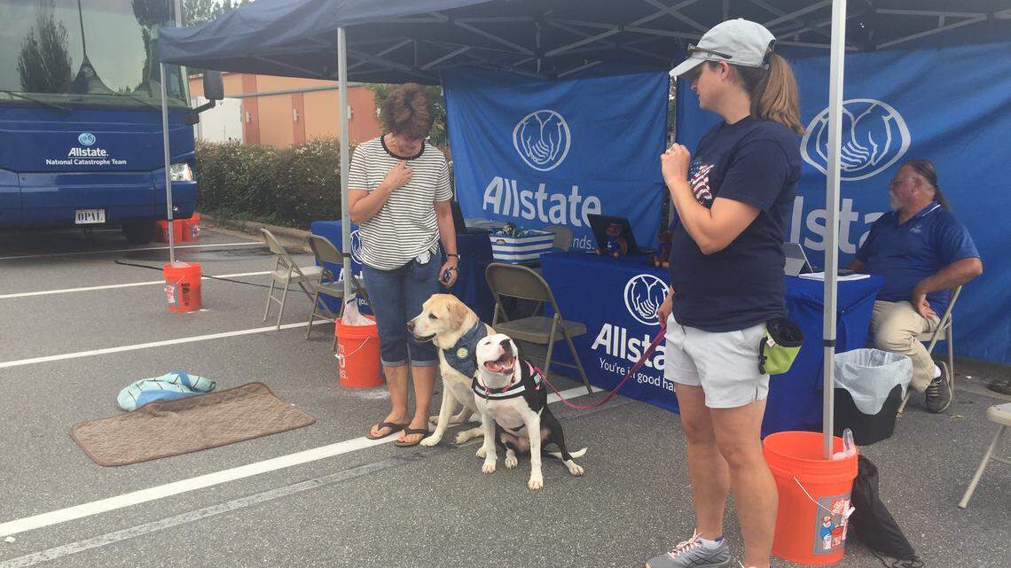 Margot Bennett, left, and Kellie Renzi stand with their therapy dogs, Brisco and Darcy, on Thursday at an insurance mobile command center as they wait for people to file claims for damage caused by Hurricane Florence.