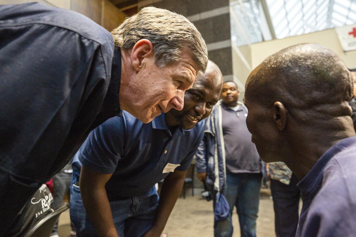 NC Governor Roy Cooper, left, speaks with Bulasi Kyungu at a shelter in Chapel Hill.