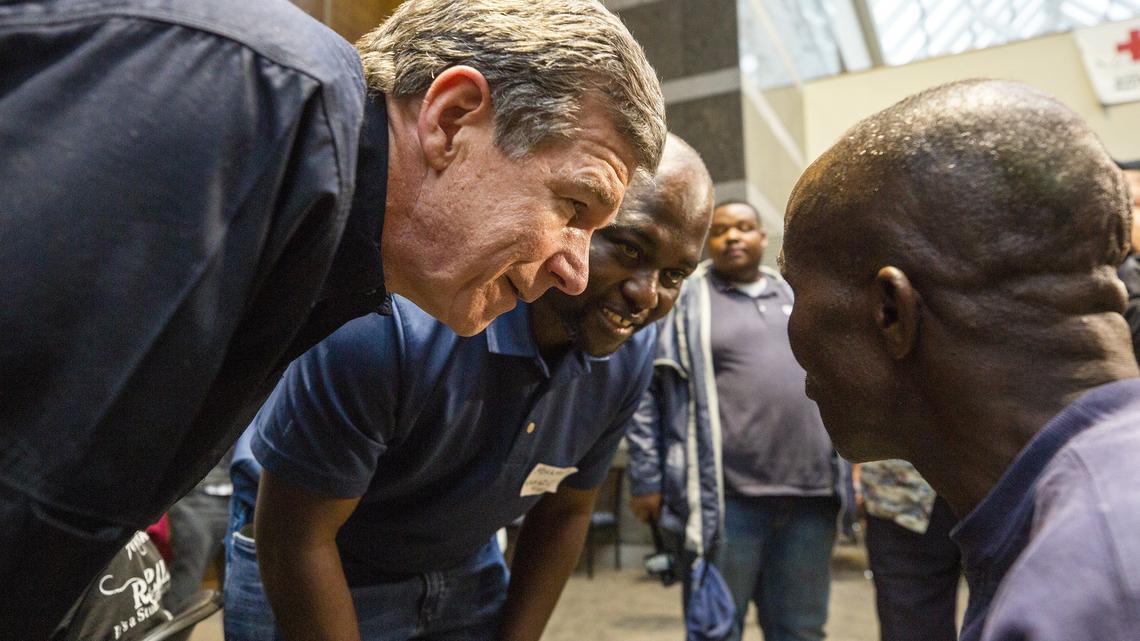 NC Governor Roy Cooper, left, speaks with Bulasi Kyungu at a shelter in Chapel Hill.