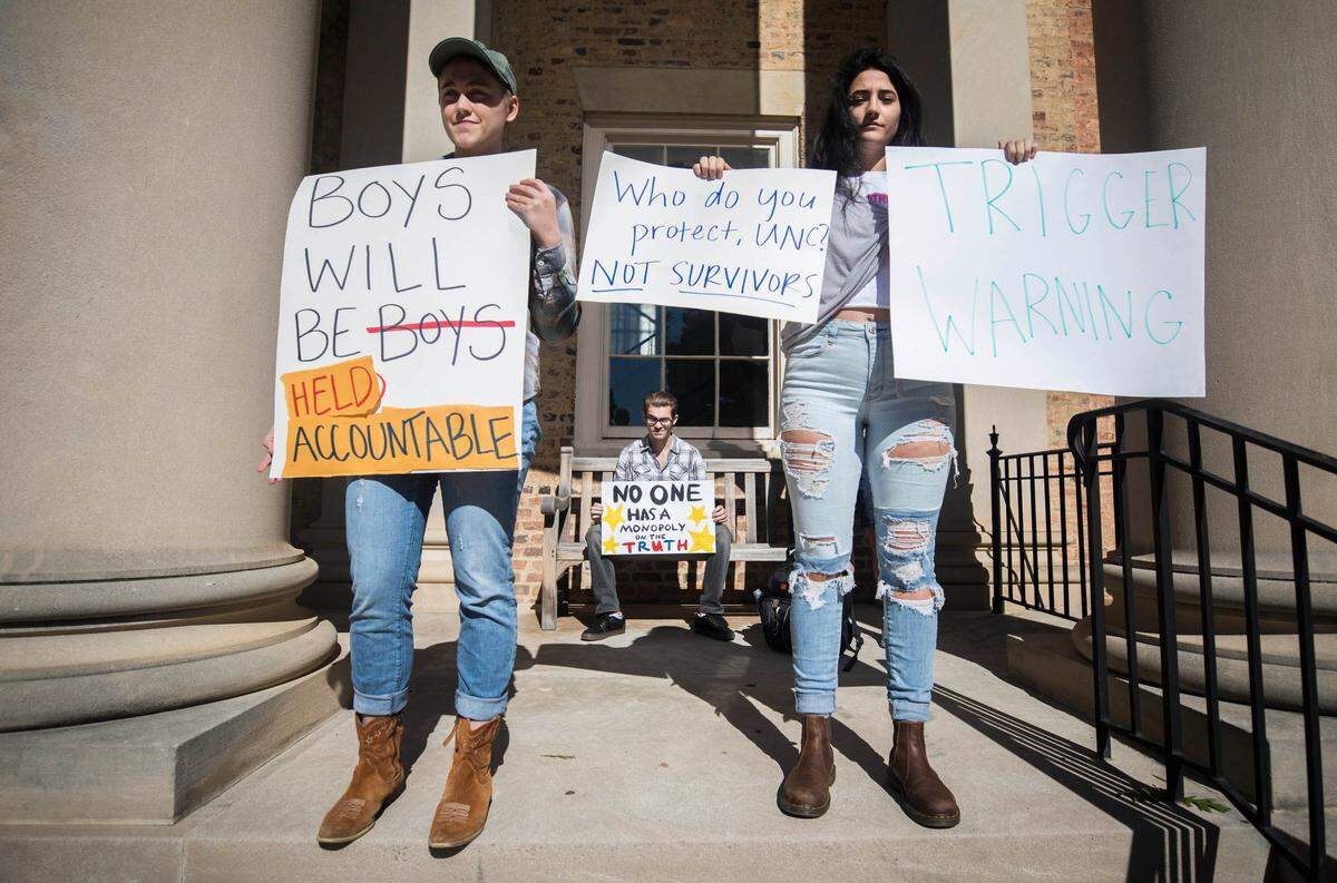 Margaret Hassel, left, and Tessa Wood, right, stand in front of a counter-protester at the #BelieveSurvivors rally. The rally was held in front of South Building on University Day, which marks UNC’s 225th birthday, on Friday, Oct. 12, 2018.