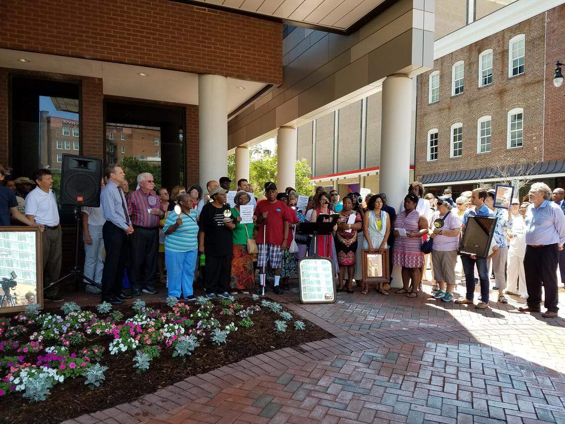 Supporters of affordable housing being built at the soon to be vacant Durham Police Department headquarters on West Chapel Hill Street held a press conference at City Hall Thursday, June 7, 2018, before the council meeting where they decided the future of the city-owned block. Reflected in the mirrors is the new downtown skyscraper, One City Center.