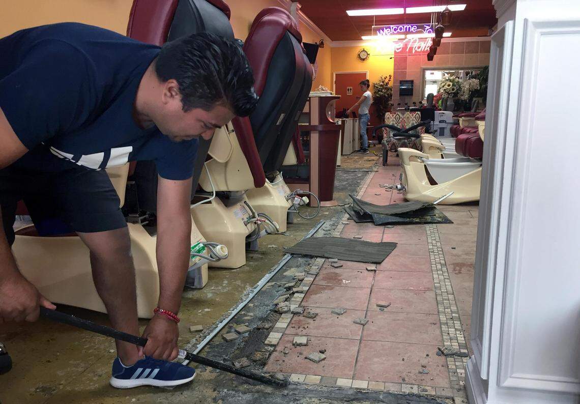 Amaure Picasso, owner of Golden Nails Construction, pries loose water-damaged tiles Thursday, Sept. 20, at Rose Nails salon in the Eastgate Crossing shopping center. The business suffered extensive damage to its floors, walls and furnishings from Hurricane Florence.