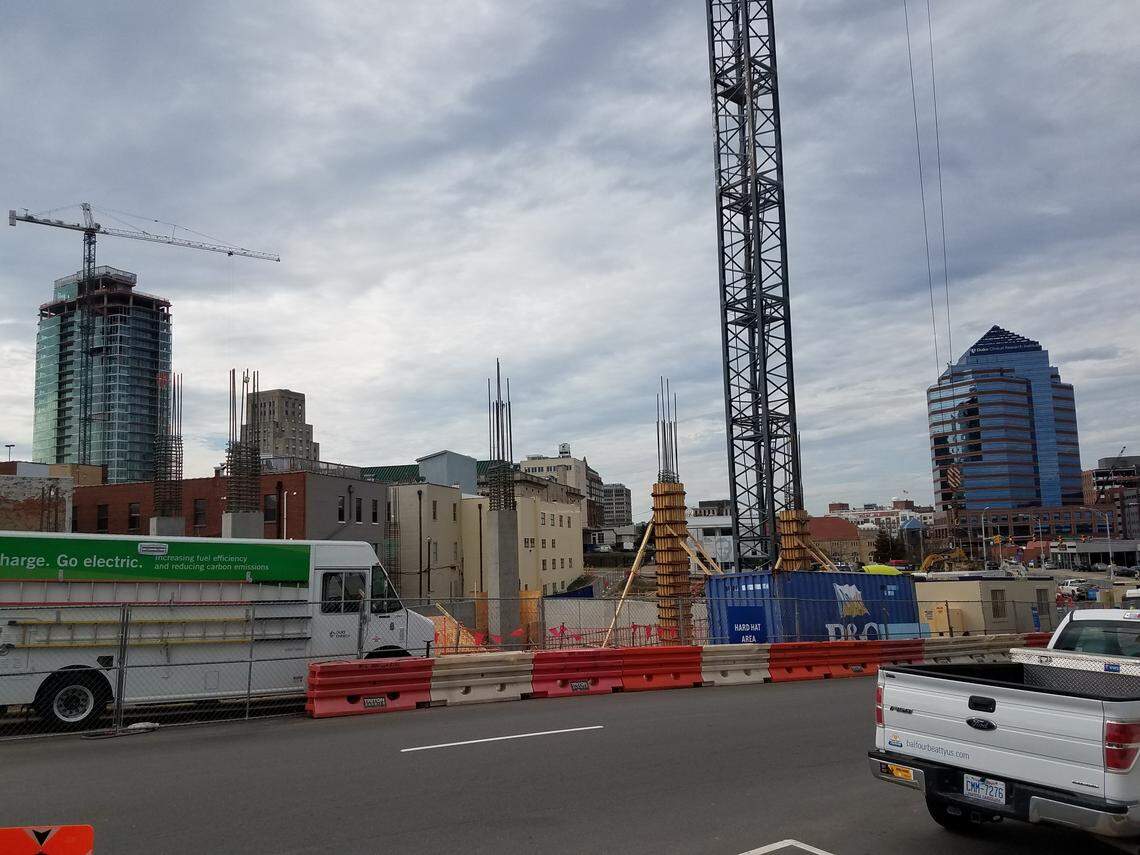 The new city mixed use parking garage, under construction in the foreground, is inside the downtown Durham loop on a one-way street, Morgan Street.