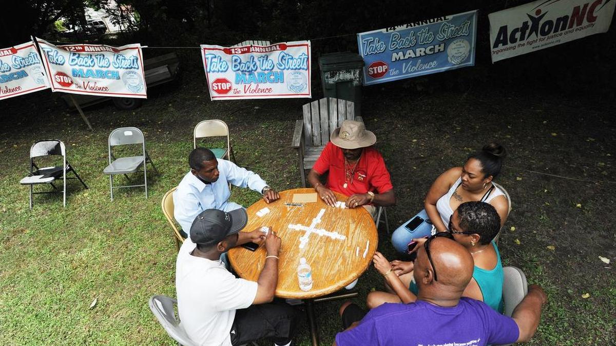 Visitors play dominoes at Saturday’s “Stop the Violence” event on Angier Avenue.