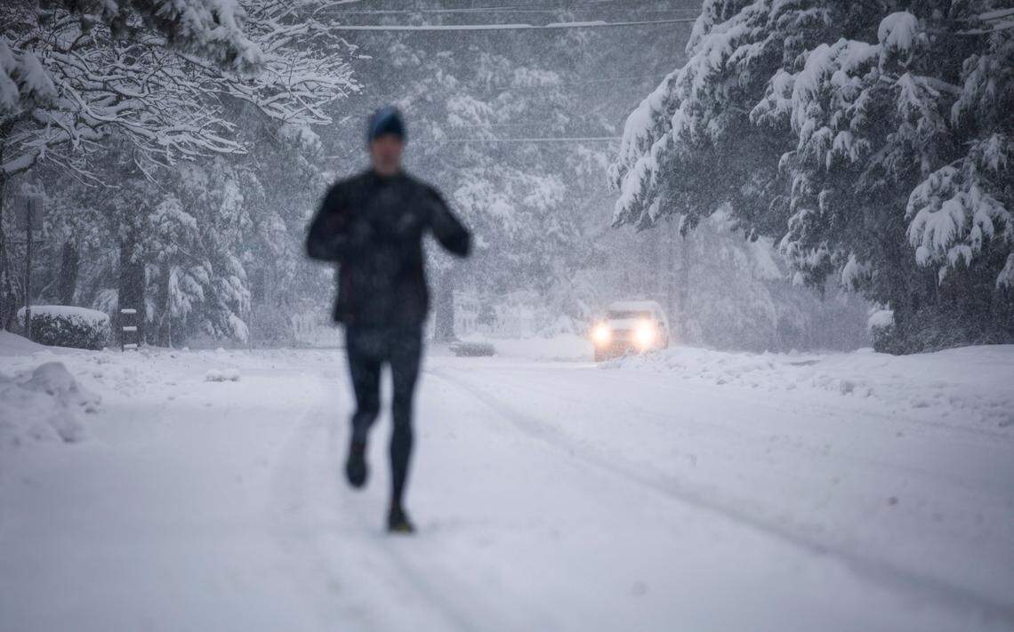 A runner and a driver brave snowy roads in Carrboro, NC on Sunday, Dec. 9, 2018.