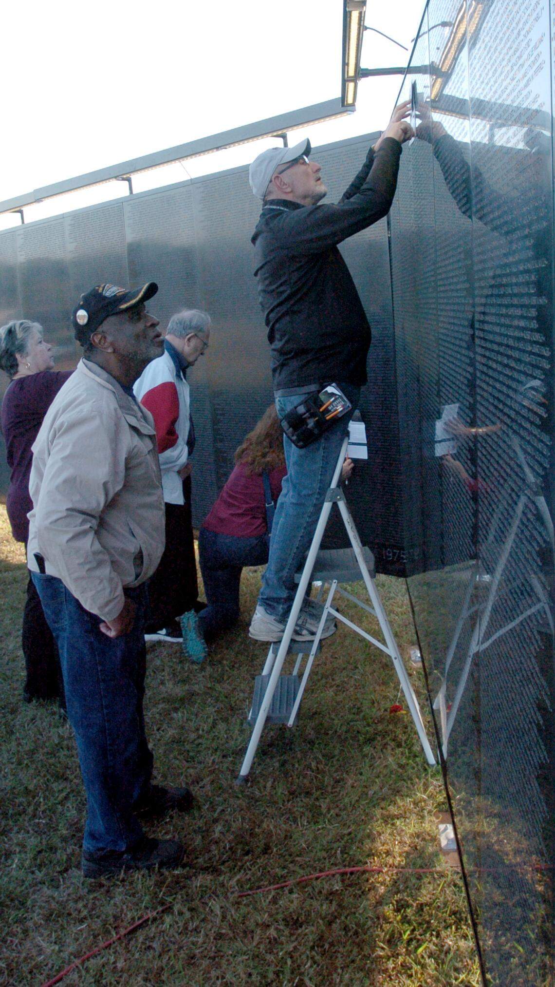 Vietnam veteran James Scott watches as a staff member from the Vietnam Veteran Memorial Fund makes a pencil rubbing of a name on the Wall that Heals, the three-quarter scale replica of the Vietnam Veterans Memorial, in Wake Forest in 2018. The wall will be in Garner March 29 to April 3.