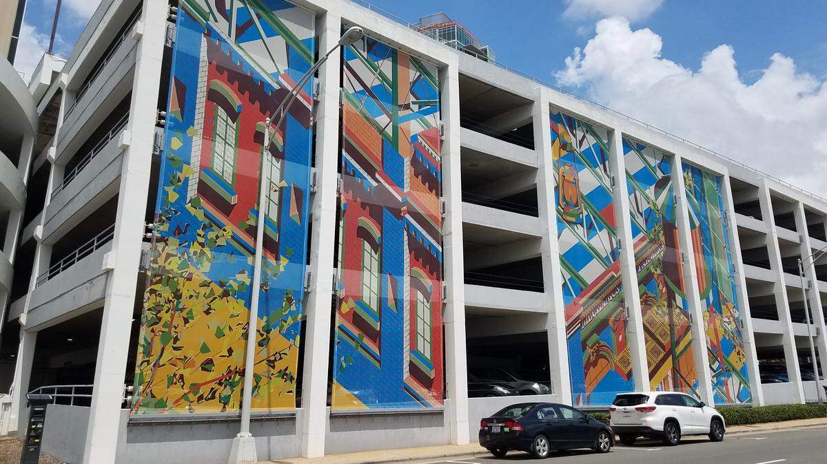 Corcoran Street parking garage, owned by the city of Durham, is now covered in public art banners by artist Olalekan Jeyifous. Another new city parking garage being built will also have public art. A Bloomberg grant will help the city find ways for people to come downtown in ways other than by car.