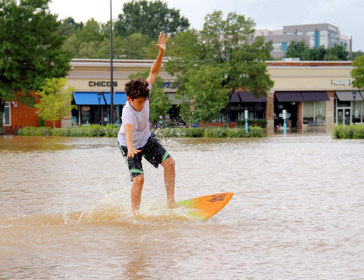 Nicholas Ebel, 12, of Chapel Hill rides a skimboard on the flooded parking lot at Eastgate Crossing shopping center in Chapel Hill on Monday, Sept. 17, 2018.