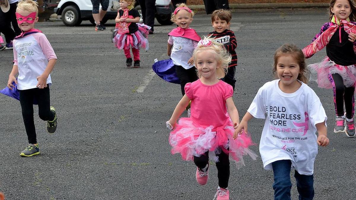 Three-year-old Emma Brooks (center) is all dressed up and running at the Susan G. Komen Triangle Race for the Cure at The Frontier in Durham’s Research Triangle Park Saturday.