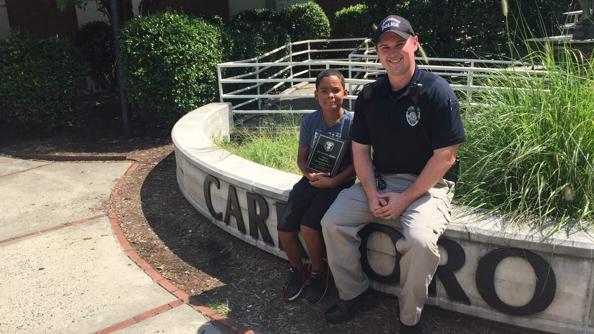 Ten-year-old Joseph Ray, left, sits with Carrboro police officer Steven Dixon on Wednesday after receiving the department’s Lifesaver Award. Ray saved a 15-month-old girl from drowning on July 4.