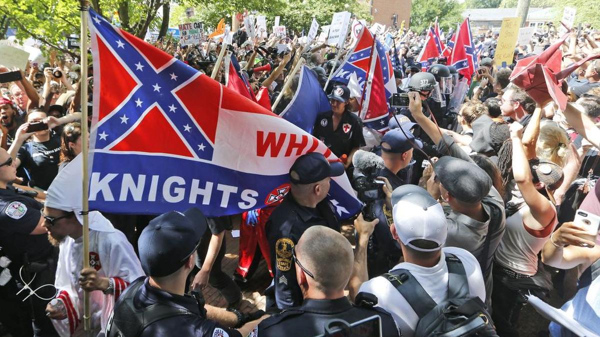 This July 8, 2017 photo shows members of the KKK escorted by police past a large group of protesters during a KKK rally in Charlottesville, Va. Some white Southerners are again advocating for what the Confederacy tried and failed to do in the 1860s: secession from the Union. So-called Southern nationalists are within the group of demonstrators who are fighting the removal of Confederate monuments around the South. They say it’s time for Southern states to secede again and become independent of the United States