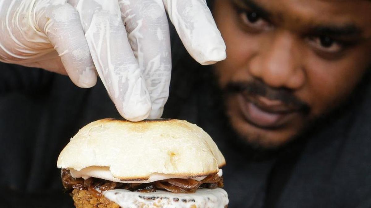 In this March 1, 2017, photo, chef Miguel Navarro inspects a Le Bleu hamburger, made with caramelized onions and blue cheese on top of portobello mushroom and lettuce, at the Atlas Meat-Free Delicatessen in Miami. When Ryan Bauhaus first started experimenting with faux meats, he fixated on recreating that subtle blood taste, settling on a tomato paste blend to mimic the acidic, iron flavor. The fatty part of meat was also not to be forgotten. Bauhaus boiled down mushrooms until he got the desired gelatinous, rubbery fat found on the back of a roast.