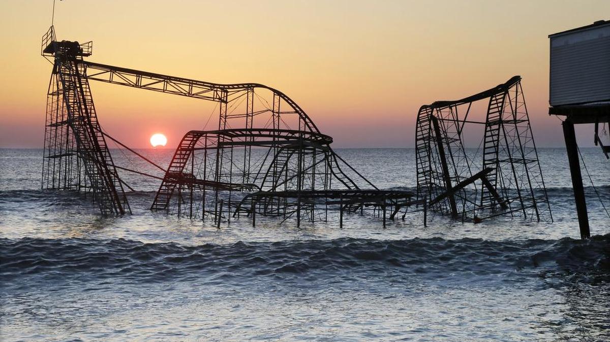 In this Feb. 25, 2013, file photo, the sun rises behind the Jet Star roller coaster, partially submerged in the Atlantic Ocean after Superstorm Sandy destroyed part of the Casino Pier in Seaside Heights, N.J. A new roller coaster named Hydrus, built safely inland above the beach rather than out over the water, opened May 6, more than four years after the storm caused billions of dollars' worth of damage to the coast.