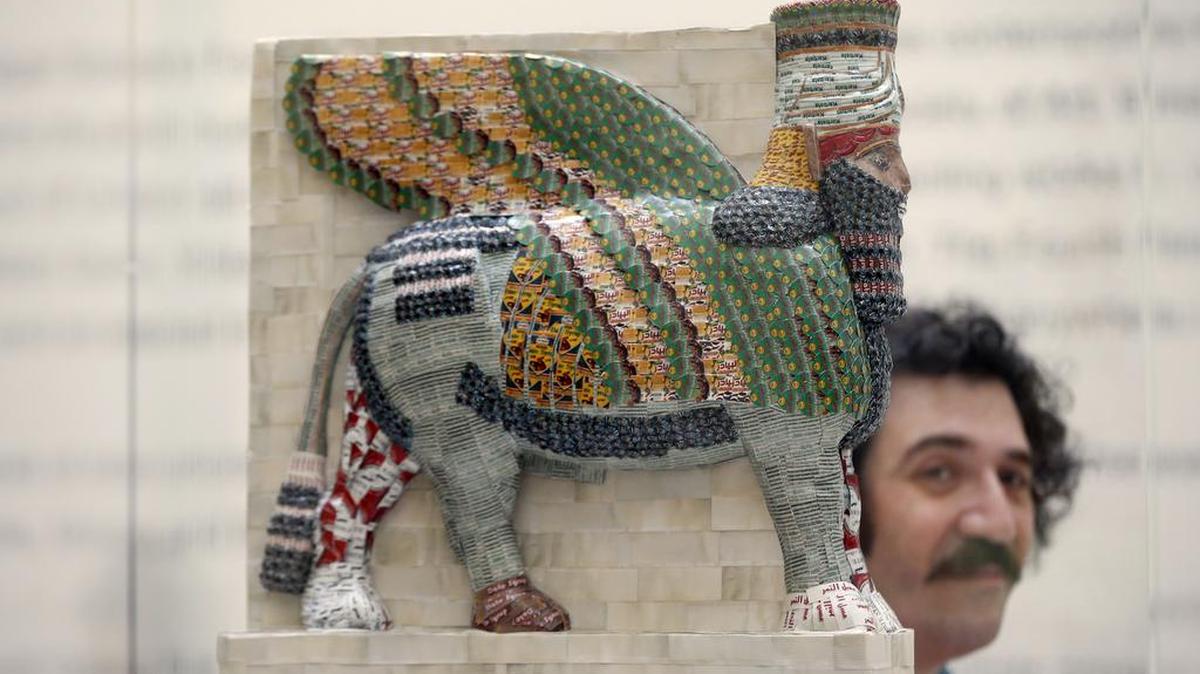 In this March 21, 2017 photo, artist Michael Rakowitz poses at the National Gallery in London next to his winning design entitled “The Invisible Enemy Should Not Exist.” A 15-foot high lamassu statue, a replica of an Assyrian winged-bull destroyed by Islamic State militants in Iraq in 2014, will soar over the tourists in London’s Trafalgar Square beginning in March 2018