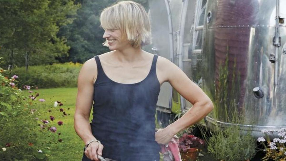 This undated photo provided by Clarkson Potter/Penguin Random House shows Erin French, owner of The Lost Kitchen restaurant in Freedom, Maine, grilling burgers with an Airstream trailer in the background. French has just come out with a cookbook called "The Lost Kitchen" that tells the remarkable story of her career from a teenager working in her dad's diner to giving dinner parties in her apartment and later in an Airstream, to running a wildly successful 40-seat restaurant in an old mill in a tiny Maine town.