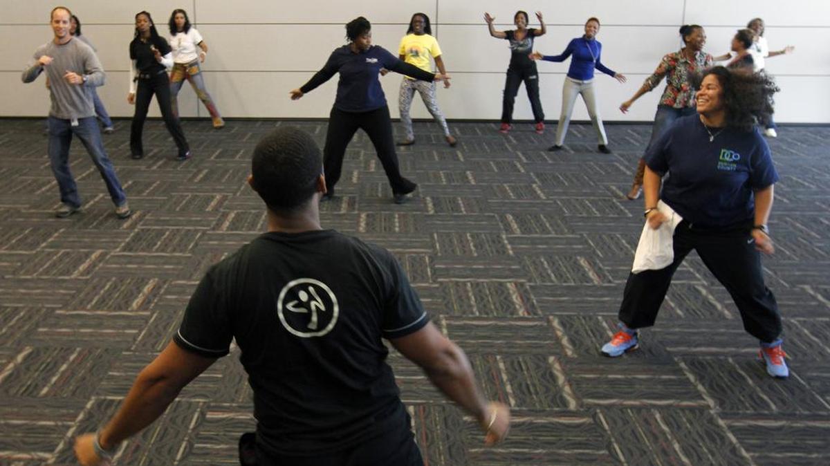 Durham County Dept. of Public Health employees and local visitors participate in a zumba session with Durham fitness consultant Derek Ross, foreground, in the Durham County Human Services building in 2013.