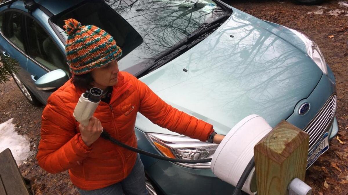 In this Thursday, April 6, 2017 photo, Sunita Halasz shows how she charges her electric car at her home in Saranac Lake, N.Y. Halasz has tips for “driving electric” along the lonely New York Adirondack Mountains roads: learn where the charging stations are, bring food and books for the kids during three-hour recharges, use the defroster in 10-second bursts since it sucks battery life, and have a backup plan.