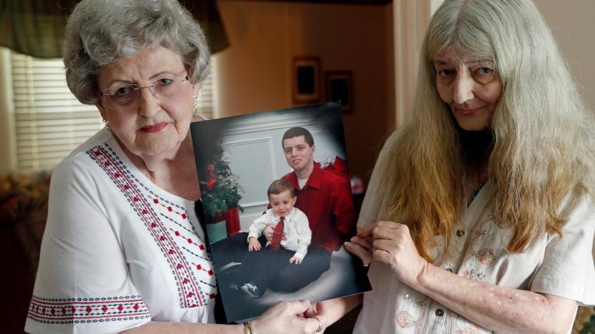 Carol Hardee, grandmother of Patrick O'Malley, left, and Kim Parker, Patrick's mother, hold a photo of him with his son Joseph. O'Malley died in 2015 of a heart attack in the Carteret County jail after being left in a restraining chair for more than nine hours.