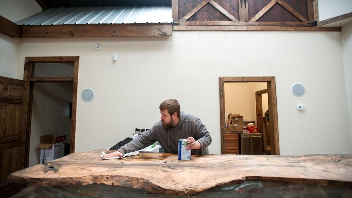 Michael Sinclair, a co-owner of the new Barrister & Brewer farm distillery in Durham County, shines the wooden bar counter in the facility’s tasting room on Dec. 29, 2016. The bar top is made of magnolia wood from Orange County.
