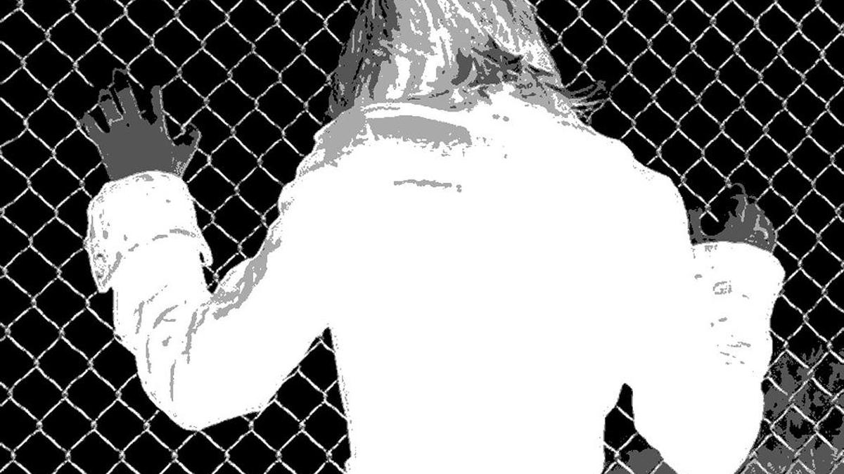A woman clutches a chain link fence.