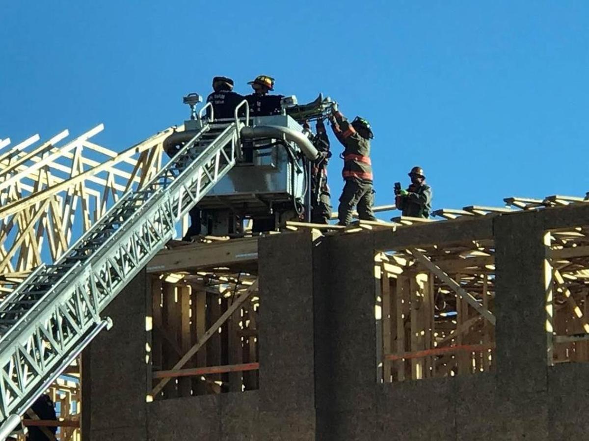 An injured construction worker is placed in a fire truck’s ladder basket, before being lowered to the ground.