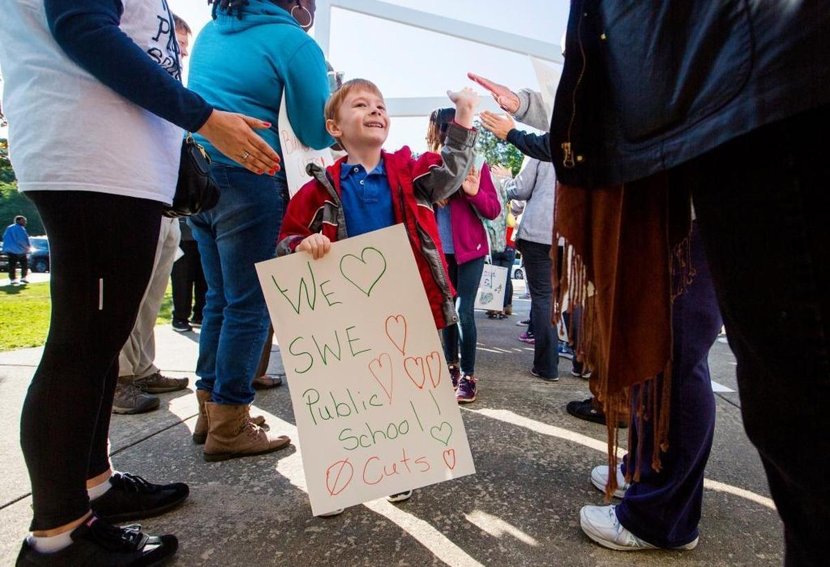 Ayden Boggs gives high-fives to parents and teachers on his way to class after a "walk-in" protest to support public education funding at Southwest Elementary School on Monday May 8, 2017, in Durham, NC. The event kicked off a "Week of Action" organized by the North Carolina Association of Educators, including schools around the state and following with events at the general assembly and town halls.