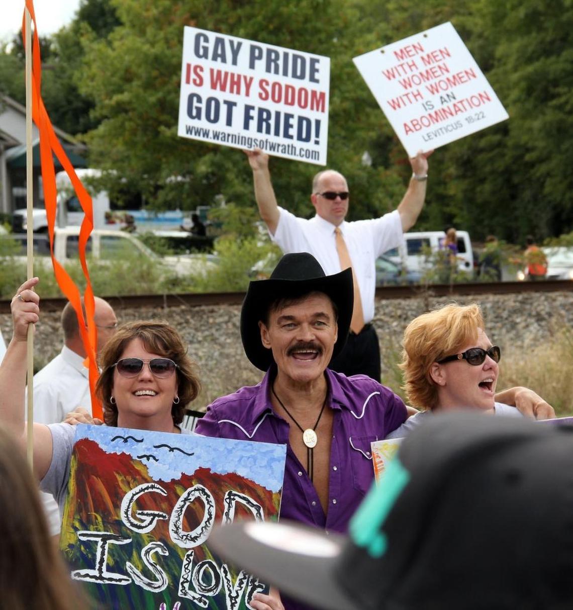 Randy Jones, the original cowboy in the pop disco group The Village People, poses for pictures in front of anti-gay preachers on Main Street. Thousands filled the Duke East Campus neighborhood Saturday, Sept. 28, 2013, for the annual N.C. Gay Pride march and rally.
