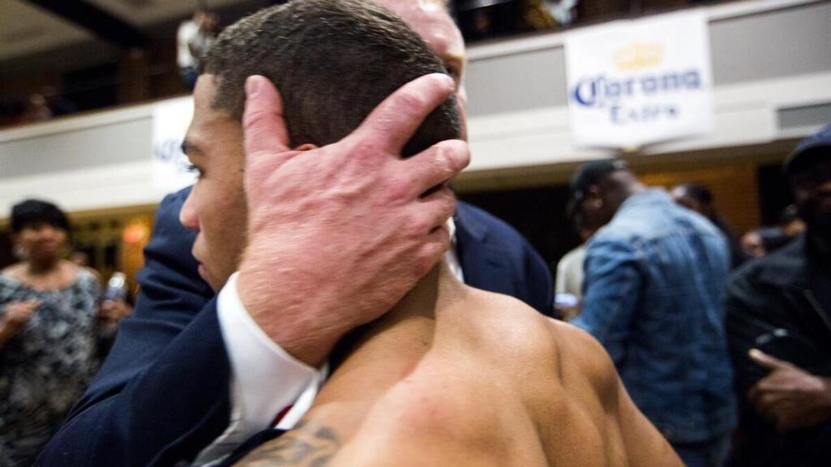 The still-reeling Marko “The Bull City Bully” Bailey receives a hug from Gardner Payne, owner and president of Payne Boxing, after being knocked out in the first round of his state lightweight title fight at the Durham Armory by Stevie “The Answer” Massey Thursday night.