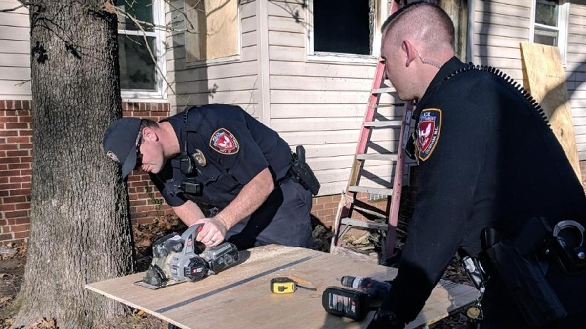 Durham police officers Bret Taylor and Daniel Johnson cut plywood panels to cover the windows and door of a house that was badly damaged in a Nov. 18, 2017, fire.