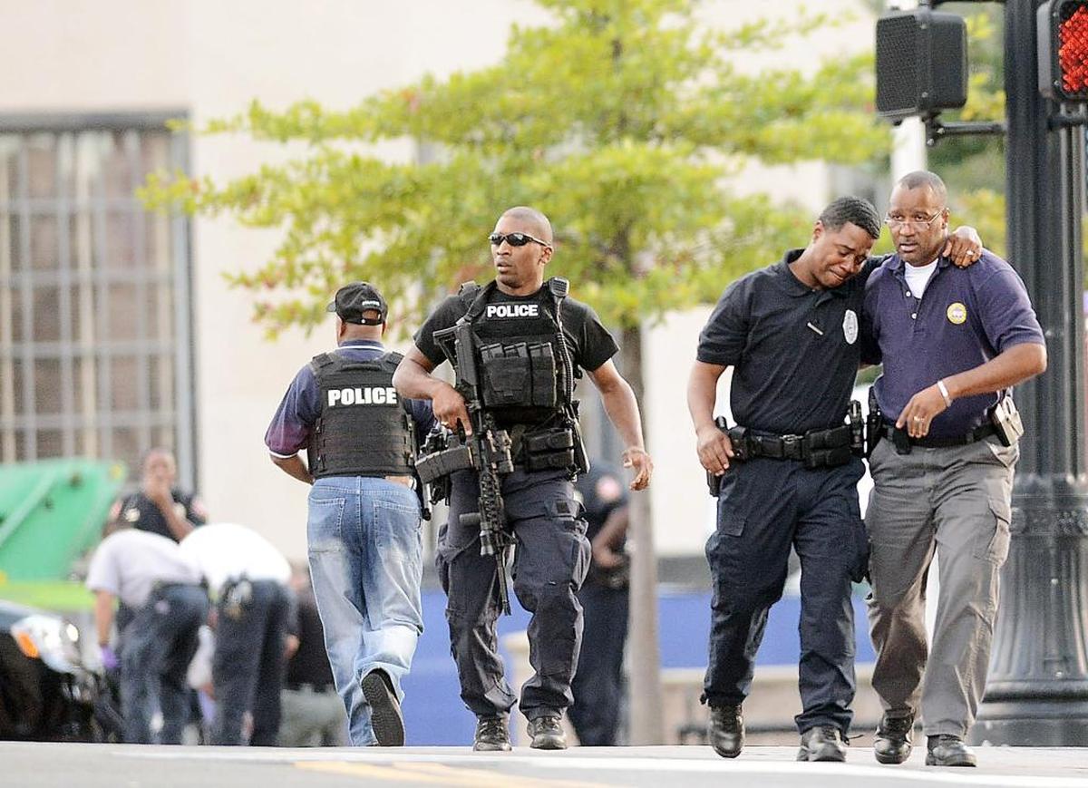 A Durham police officer comforts Lt. Lamont Minor, second from right, in this 2013 file photo taken after police killed a suicidal man in an armed standoff downtown. Minor had unsuccessfully negotiated with the man for nearly an hour to put down his weapon.