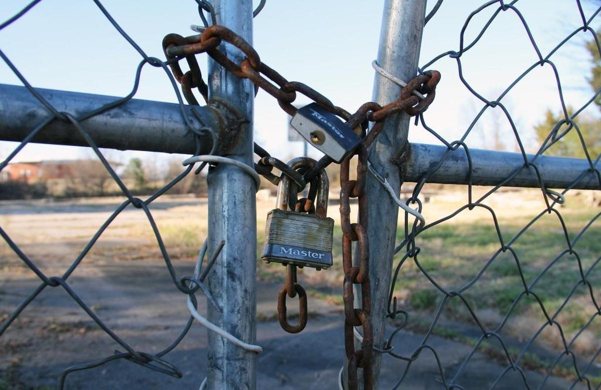 A lock secures a chain link fence around Fayette Place, a largely abandoned former public housing community site just south of downtown Durham.