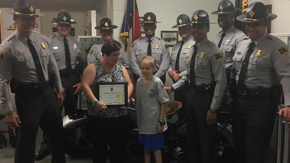Howell Brown III stands next to his mother, Susan Brown, surrounded by N.C. Highway Patrol troopers on the day of his own induction into the State Highway Patrol, as an Honorary Trooper.