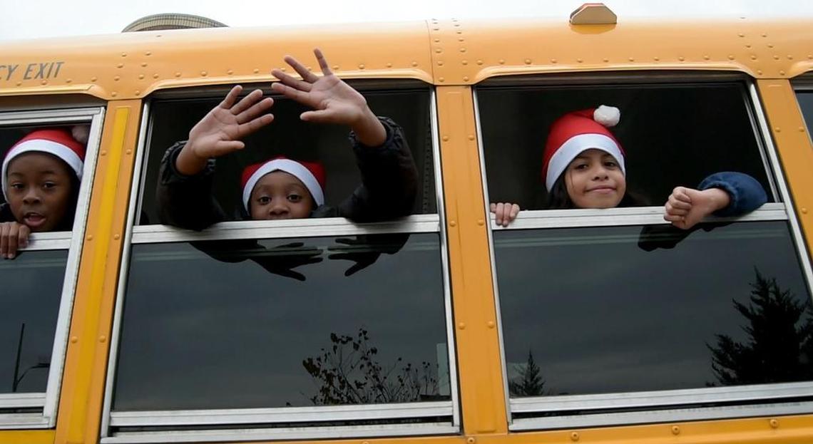 Healthy Start Academy students cheer from their school bus during a Durham Holiday Parade on Main Street.
