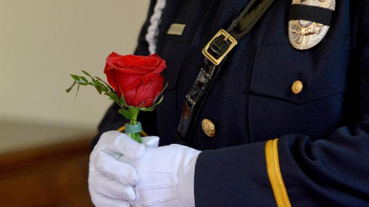 An officer holds a lone rose to honor fallen officers during the annual Durham Peace Officers Memorial Service Friday at Grey Stone Church on Hillsborough Road. Law enforcement officers who died in the line of duty and their families were honored.