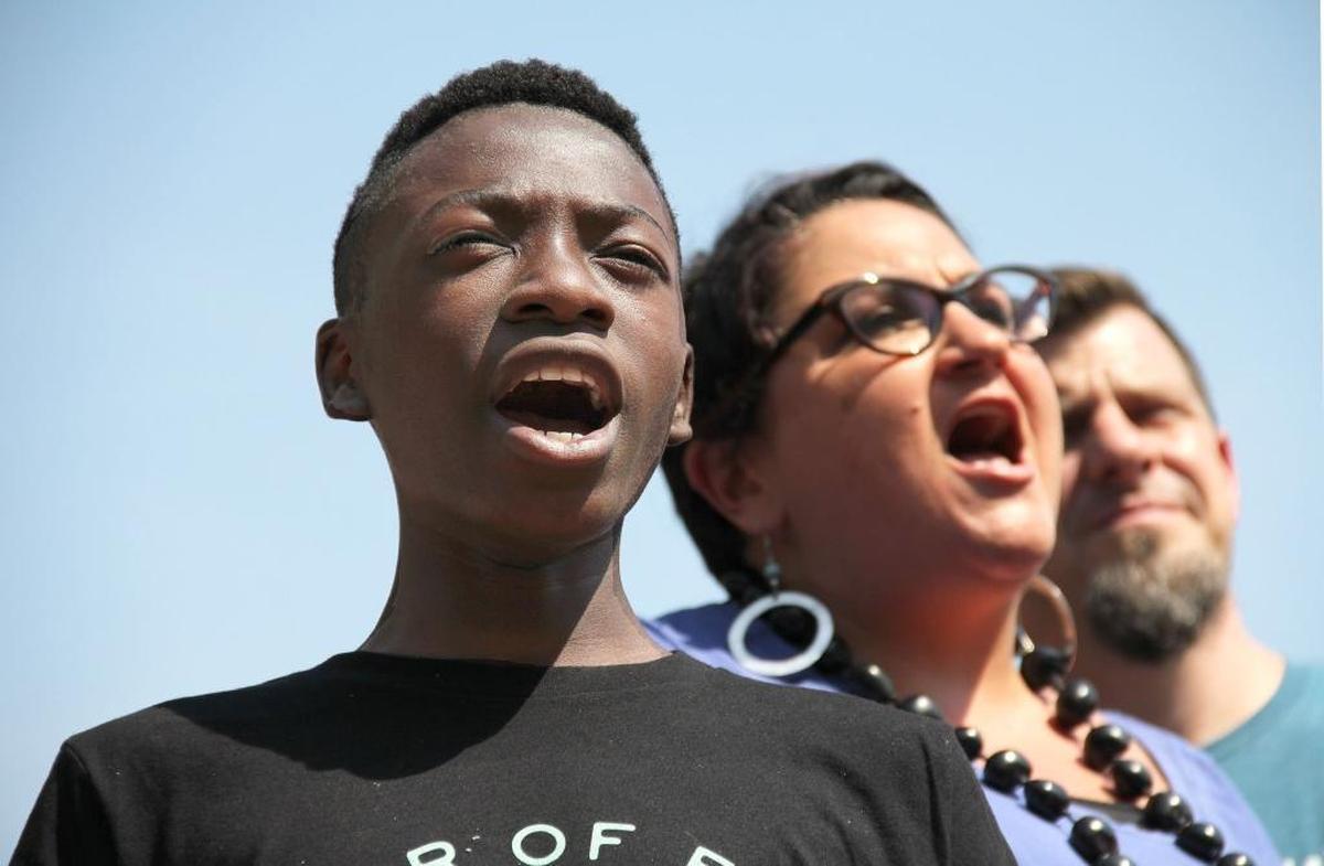 "I believe we should fight for what we want," says Nico Mangine, 12, with his mother Gwenn Mangine of Cary on Monday, Sept. 4, 2017. About 175 people rallied on CCB Plaza in downtown Durham for a $15 per hour wage and the right to unionize for fast-food and other service-industry workers.