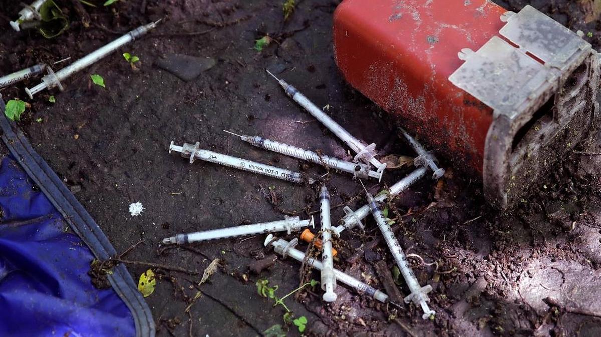 This Wednesday, June 7, 2017 photo shows discarded used hypodermic needles without protective sheaths at an encampment where opioid addicts shoot up along the Merrimack River in Lowell, Mass. Syringes left by drug users amid the heroin crisis are turning up everywhere. They hide in weeds along hiking trails and in playground grass, get washed into rivers and onto beaches, and lie scattered about in baseball dugouts and on sidewalks and streets. There are reports of children finding them and getting poked.