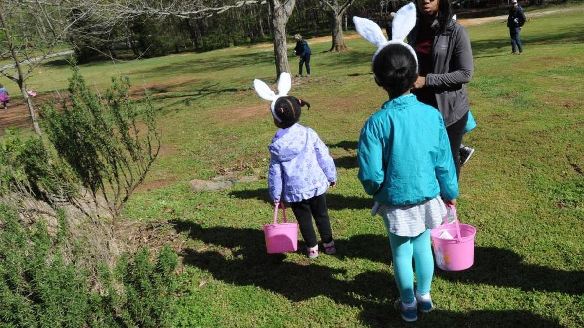 Morgan Williams and sister Lauren Williams (center) are pictured with mom Christina Williams as they prepare to take part in Saturday’s Easter egg hunt at West Point on the Eno.
