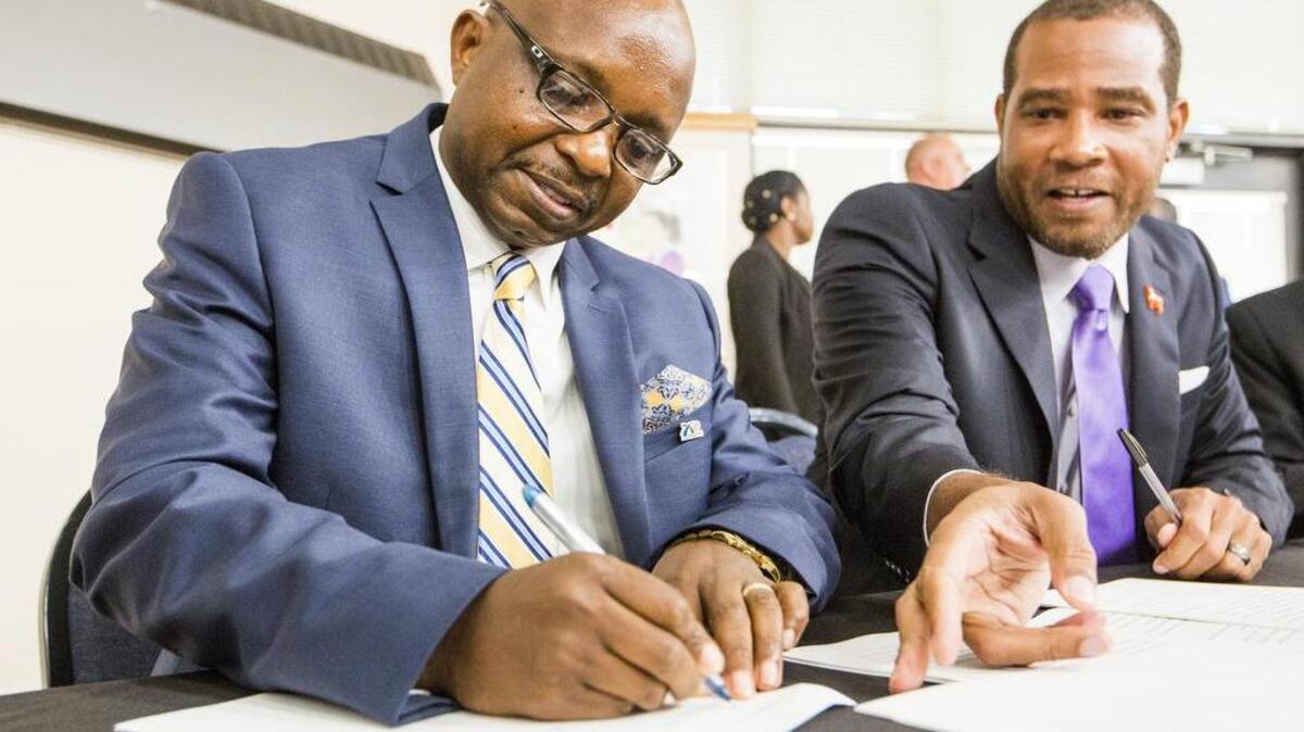 New Durham Public Schools Superintendent Pascal Mubenga (left) signs his contract on Oct. 16.