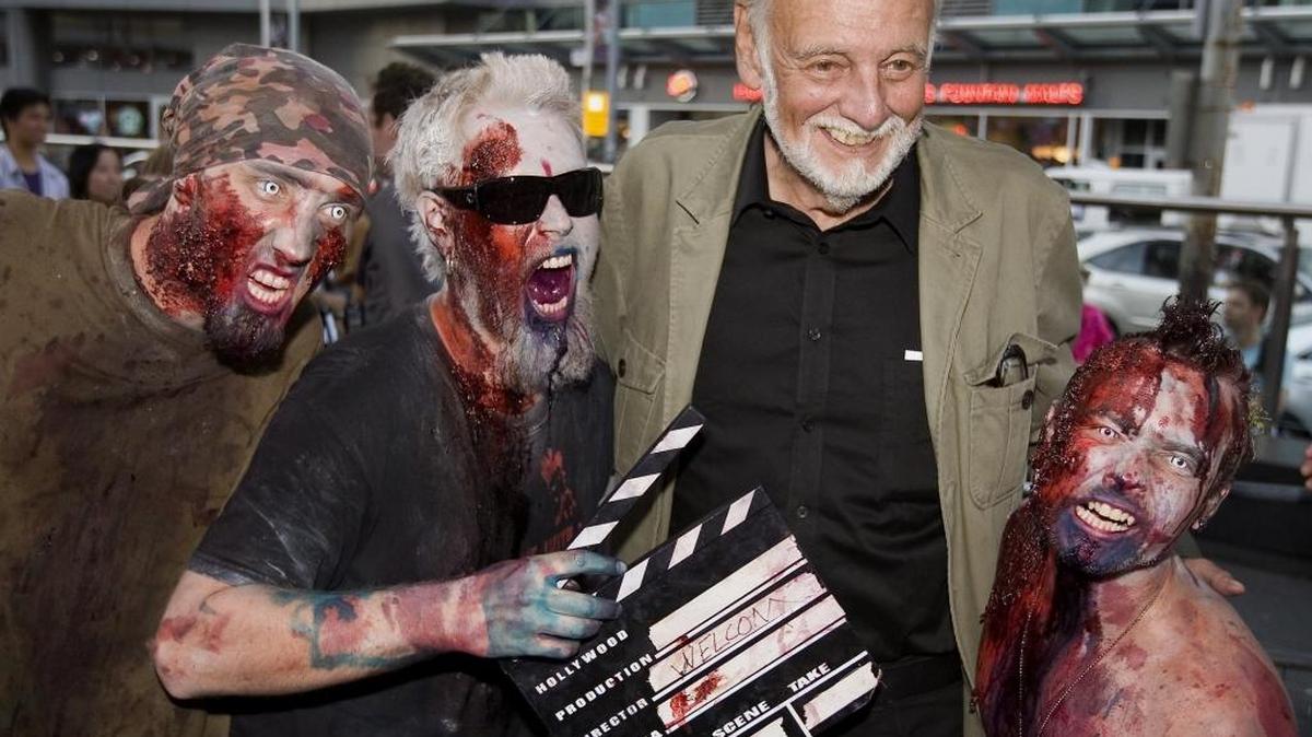 In this Sept. 12, 2009, file photo, director George Romero poses with some fans dressed as zombies after accepting a special award during the Toronto International Film Festival in Toronto. Romero, whose classic "Night of the Living Dead" and other horror films turned zombie movies into social commentaries and who saw his flesh-devouring undead spawn countless imitators, remakes and homages, has died. He was 77. Romero died Sunday, July 16, 2017, following a battle with lung cancer.