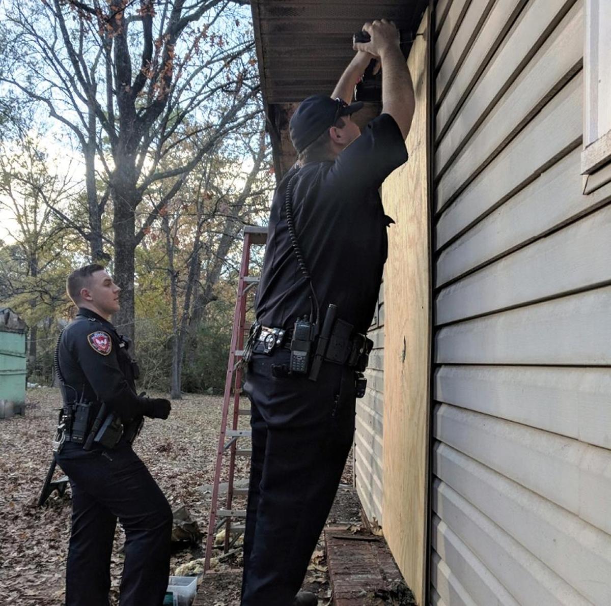 Durham police officers Bret Taylor and Daniel Johnson screw plywood panels over the side door to a house that was damaged in a Nov. 18, 2017, fire.
