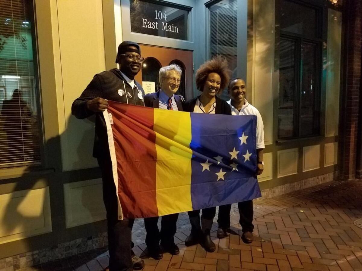 People's Alliance candidates celebrate outside 106 Main on election night Nov. 7, 2017, holding the City of Durham flag. From left are John Rooks Jr., Mayor-elect Steve Schewel and council members-elect DeDreana Freeman and Vernetta Alston.
