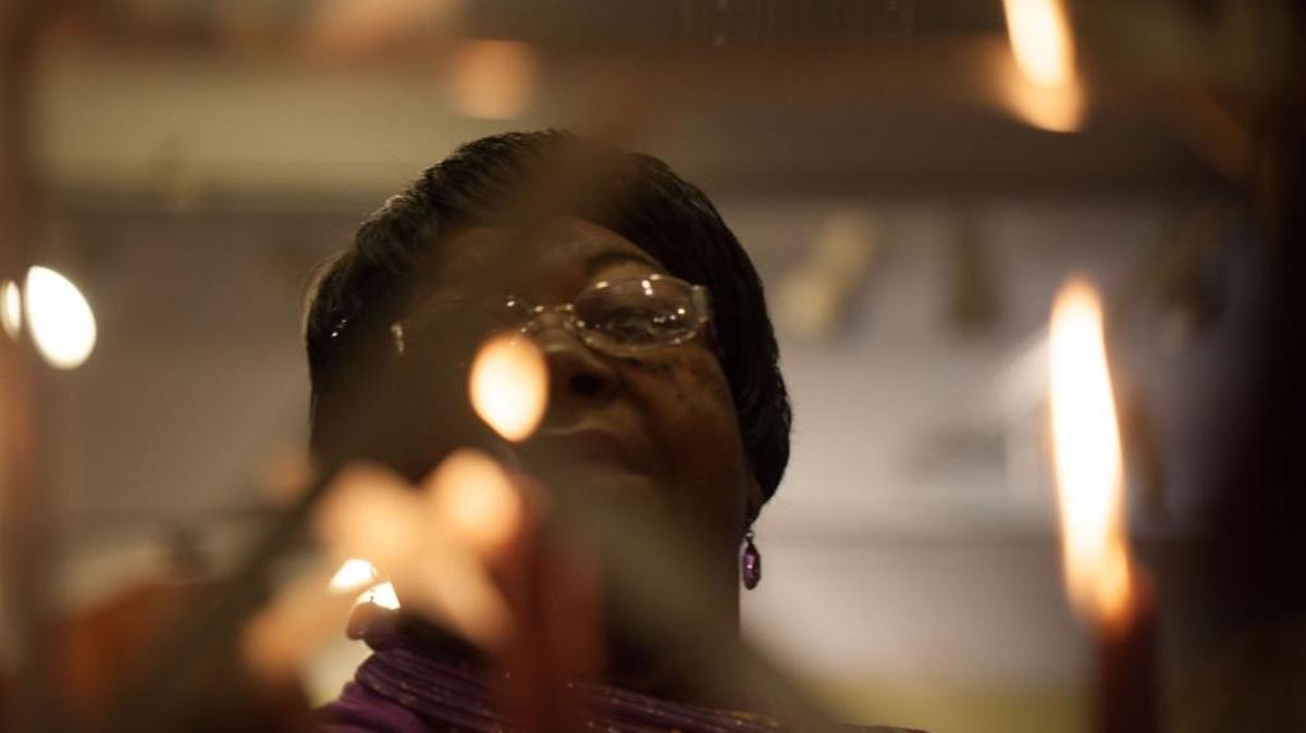 Effie Steele, board chair of the Religious Coalition for a Nonviolent Durham, lights a candle at a vigil in 2016.