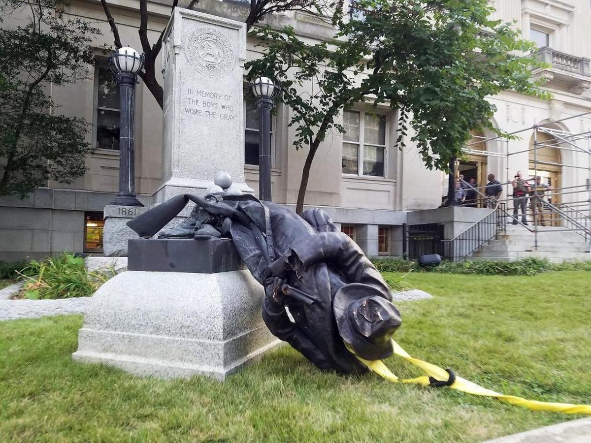 A Confederate statue lies damaged and partly torn from its pedestal after a demonstrator looped a moving strap around it in August 14, 2017, and a group pulled it to the ground. The group was protesting a deadly clash between white supremacists and counterprotesters in Charlottesville, Virginia, the day before.