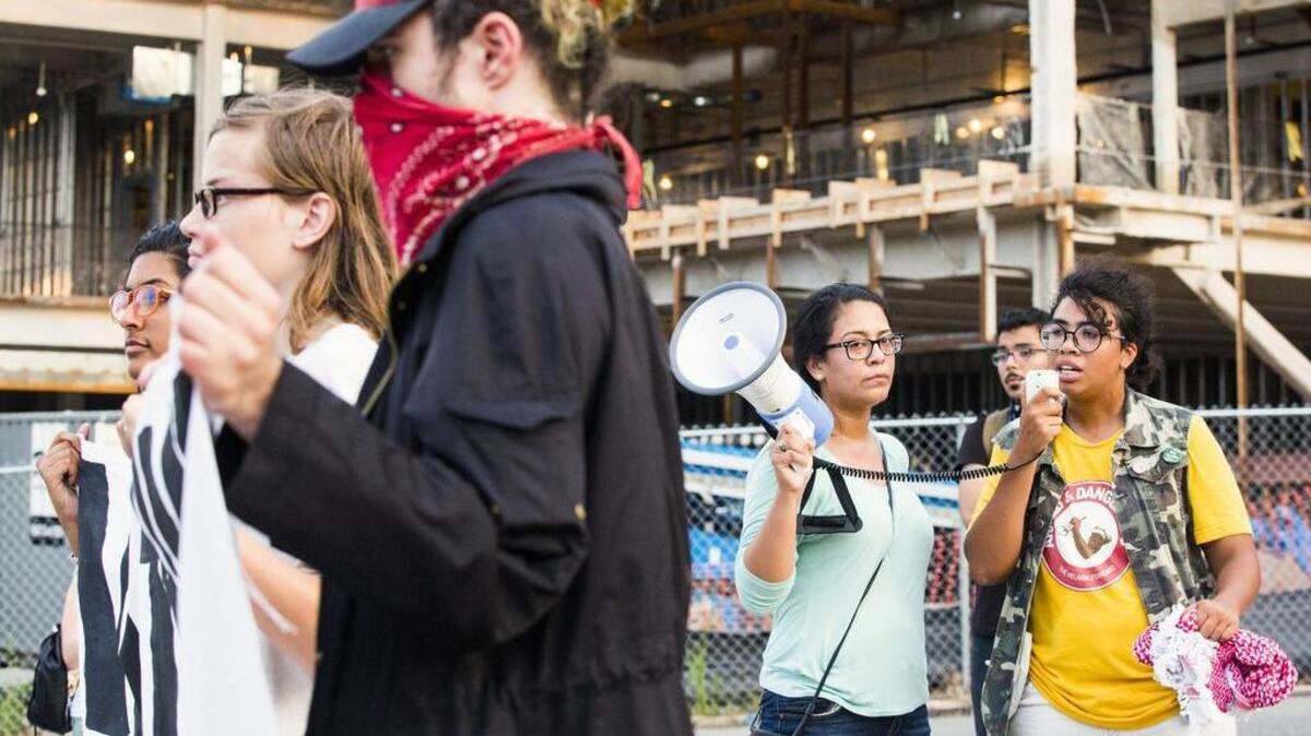Qasima Wideman, right, speaks through a megaphone to a group of protesters gathered gathered the site of the new police headquarters, still under construction, after they toppled a Confederate soldier statue at the old Durham County Courthouse during an 'Emergency Durham Protest' in response to the violent protests Saturday in Charlottesville, on Monday, Aug. 14, 2017, in Durham, NC.